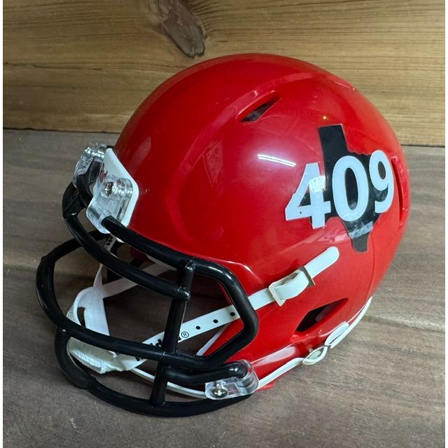 Beaumont Renegades Mini Helmet. Candy apple red shell with a black facemask, back view. White '409' numerals over a black Texas outline near the rear of the shell.