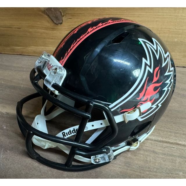 Albany Firebirds Mini Helmet. Black shell with a black facemask. Angular red-and-white firebird wing logo on the side with a red center stripe running front to back.