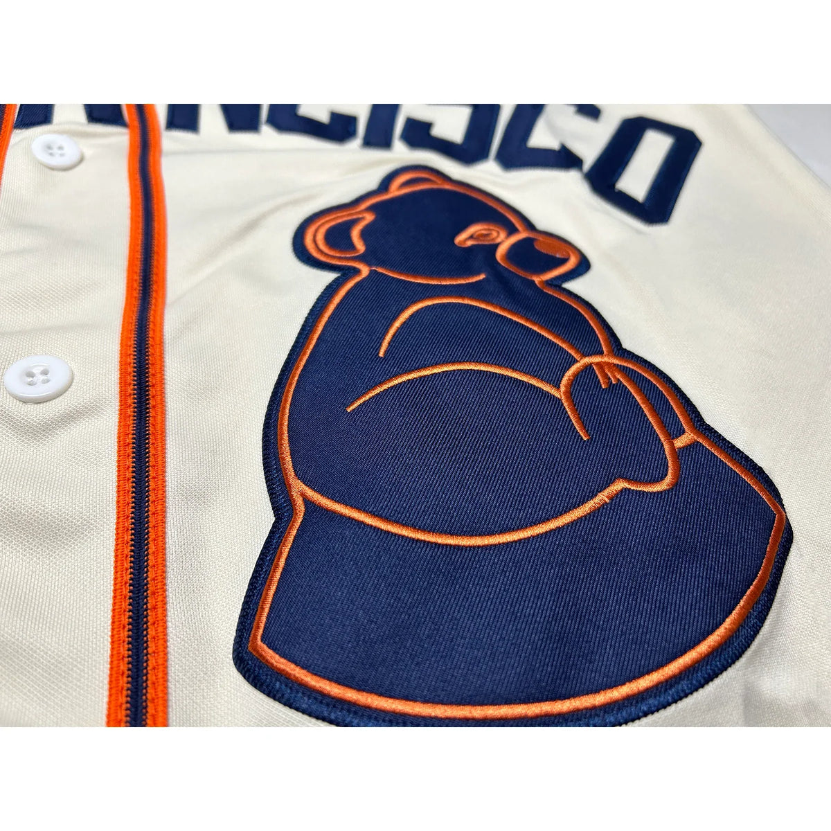 San Francisco Sea Lions NLB Jersey close-up of sea lion crest, navy with orange trim on cream fabric.