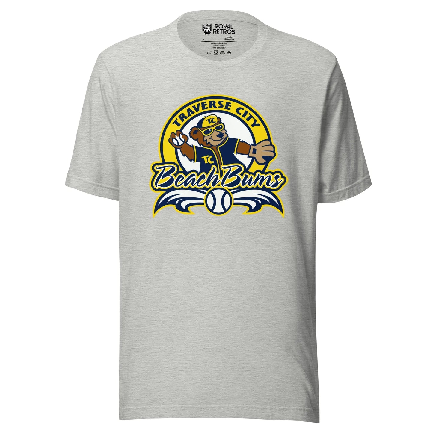 Traverse City Beach Bums baseball T-shirt. Gray. Yellow circle with Traverse City arched inside across top. Inside with bear in blue jersey and yellow cap throwing a baseball. Beach Bums in script across bottom of circle with baseball in middle and decorative wings coming off sides. Royal Retros