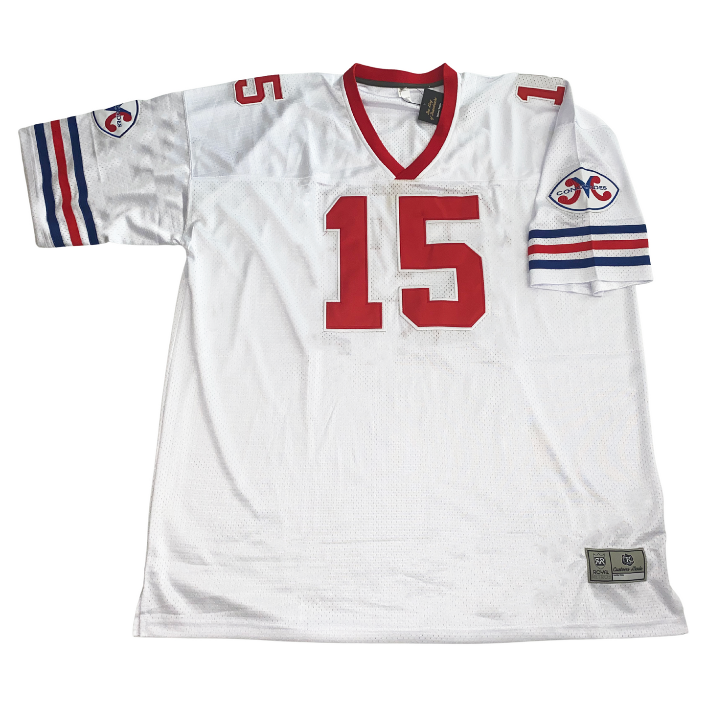 Montreal Concordes Jersey white. Red collar. Blue, red, and blue thin stripes on sleeve ends. Red #15 large on chest, small on shoulders, Concordes logo on shoulders, consisting of stylized red M in white oval with white border. CONCORDES in blue across M. Royal Retros