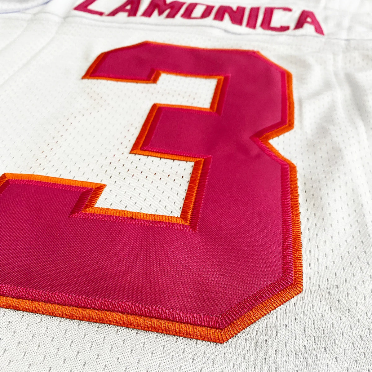 Southern California Sun WFL Jersey close-up of back nameplate and number. 'Lamonica' in pink with orange trim above number 3, on white mesh fabric.