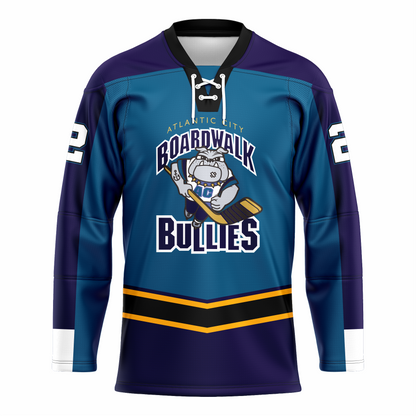 Atlantic Boardwalk Bullies ice hockey jersey. Teal. Purple shoulders. Sleeves are half purple. On chest is Cartoon bulldog skating toward viewer holding hockey stick. Bullies in purple with white and teal trim. Black band with gold trim above west, purple below. Royal Retros