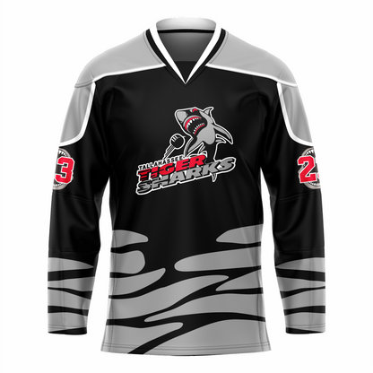 Tallahassee Tiger Sharks hockey jersey. Black. Black and white collar, silver shoulders with white trim. Random silver pattern at sleeve ends and around waist suggesting ocean waves. Logo is a shark swimming toward viewer with Tallahassee small in black with white trim above Tiger  in red and Sharks in silver. Royal Retros