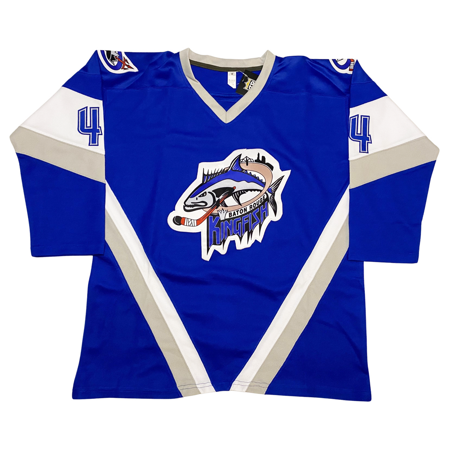 Baton Rouge Kingfish hockey jersey. Blue. Silver collar. Angled white and silver bands on sleeves and angled from mid-chest to waist to from a V. #4 blue with black trim on white band on shoulder. Kingfish logo center chest. Big blue catfish holding hockey stick, facing left. Stylized Baton Rouge Kingfish below. Royal Retros