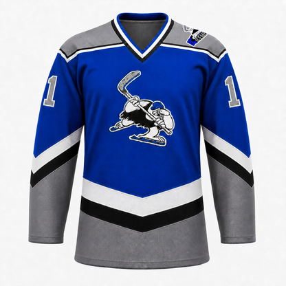 B.C. Icemen hockey jersey front in royal blue with grey shoulders and lower body, black and white chevron striping, and the cartoon penguin mascot crest at center chest