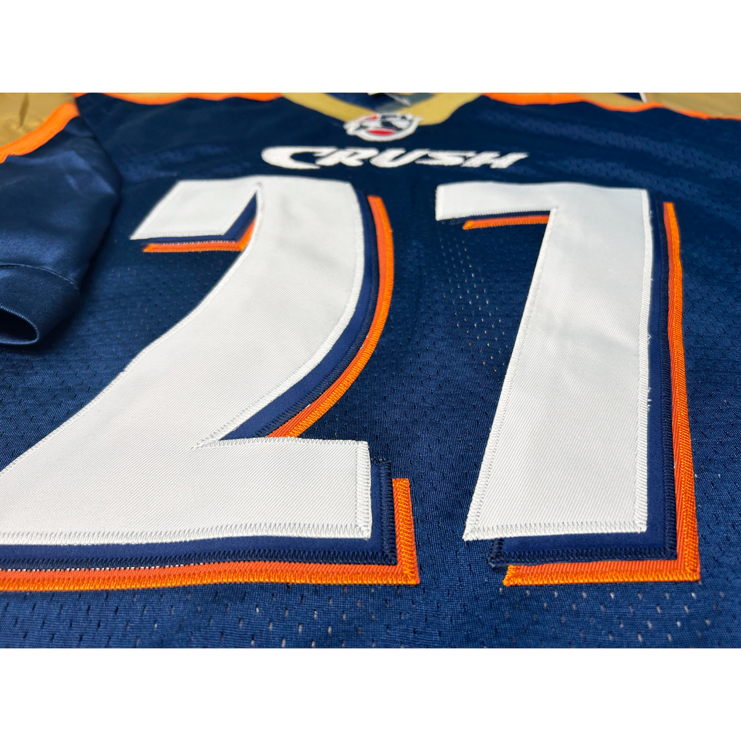 Close-up of Colorado Crush football jersey. #27 in white with orange trim on blue. Royal Retros.