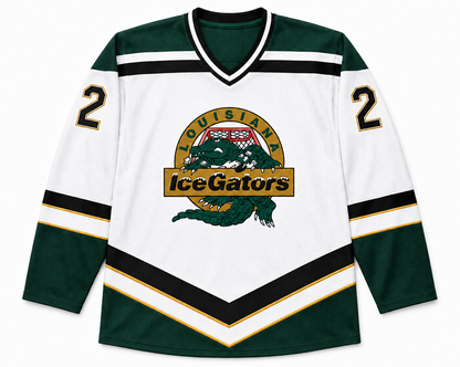 Louisiana IceGators hockey jersey. White body with dark green shoulders, sleeves and hem. Black and gold chevron stripes angled from mid-chest down to the waist and banded around each sleeve. White V-neck collar with green trim. Black number 2 on each shoulder. IceGators crest on the center chest: a green alligator on a gold circle, LOUISIANA arced above, IceGators across a gold banner. Royal Retros