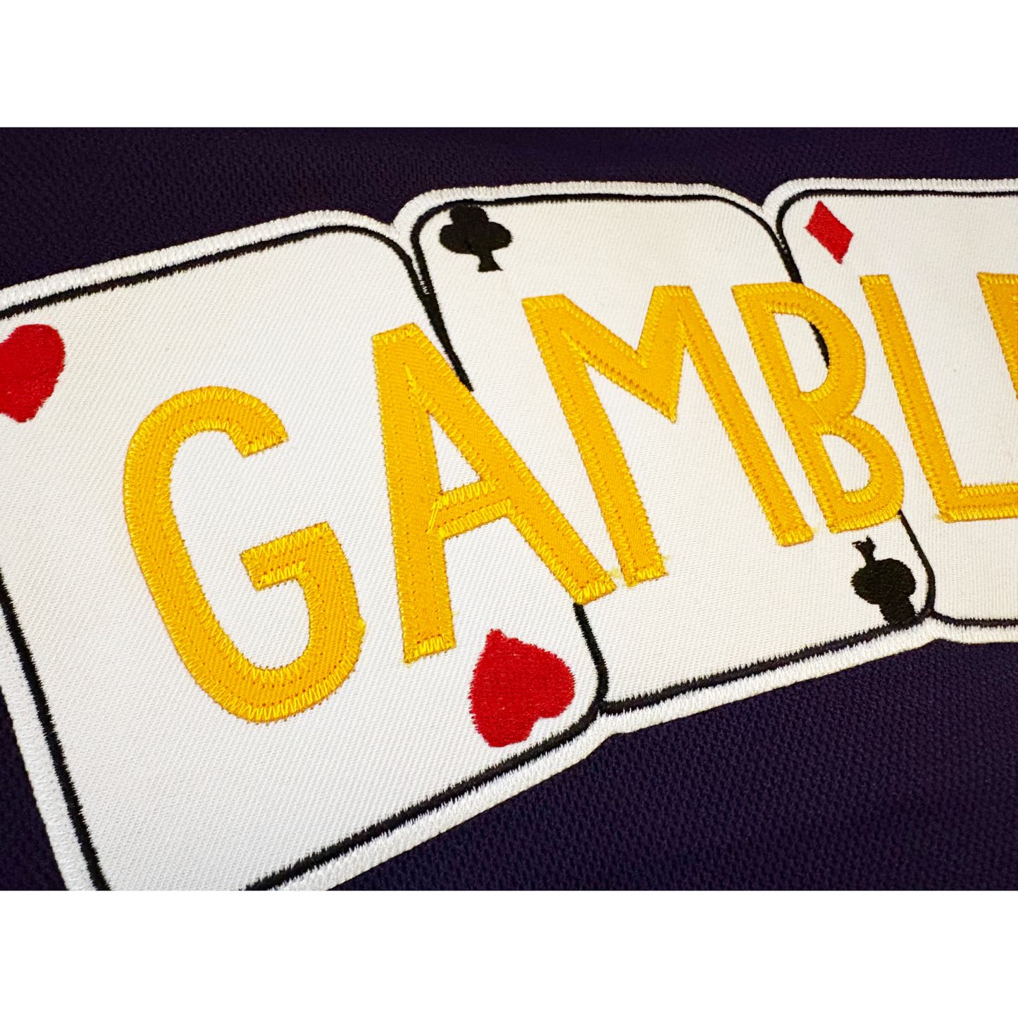 Close0up of Las Vegas Gamblers Jersey, purple. Gamblers in gold across 4 playing cards (hearts, clubs, diamonds, spades, outlined in black and white. Royal Retros.