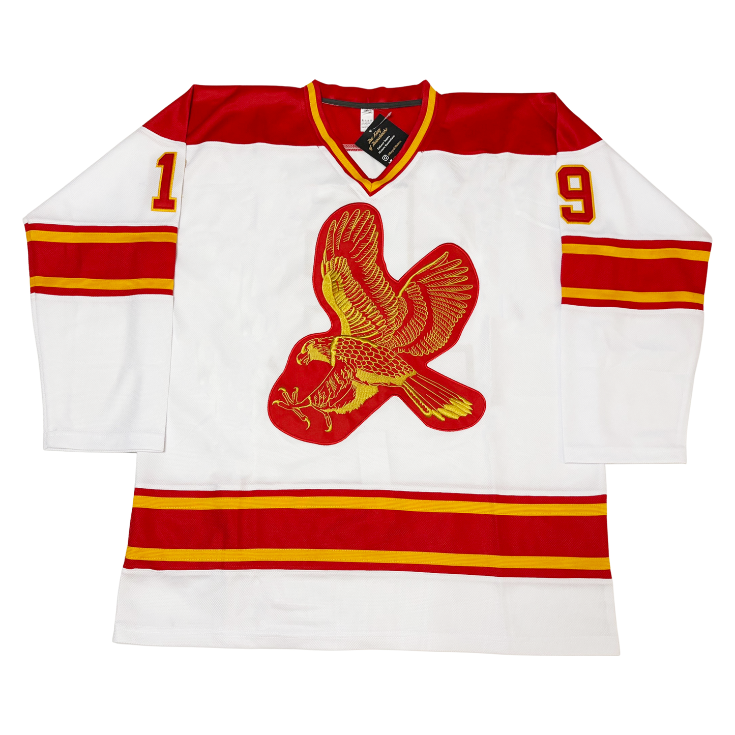 Salt Lake Golden Eagles hockey jersey. White. Red shoulders. Thin red, thin gold, thick red, thin gold, thin red bands at mid-sleeve and above waist. Numbers on shoulders in red with gold trim. Logo an chest is an image of a red and gold eagle, wings up as it diving on prey. Royal Retros