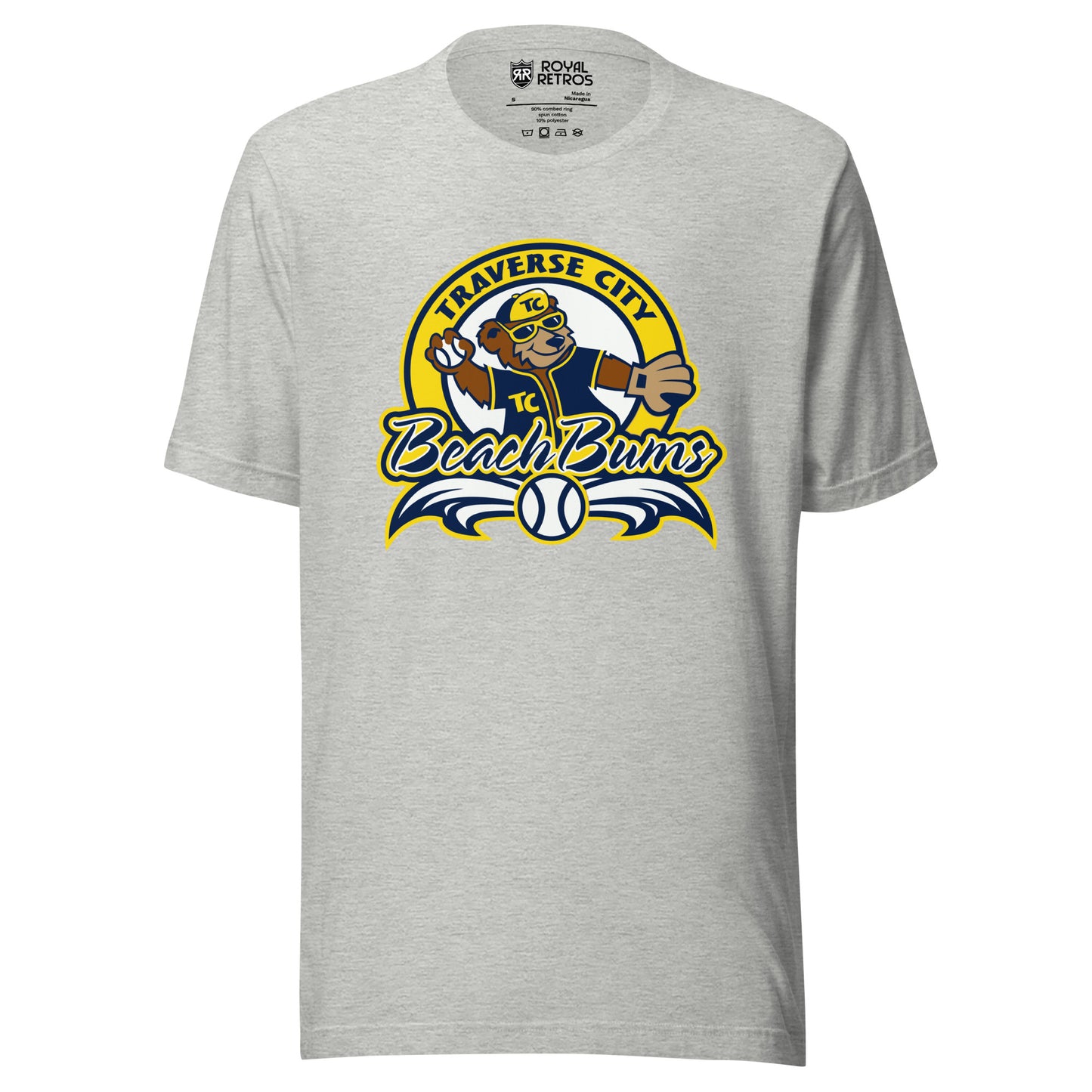 Traverse City Beach Bums baseball T-shirt. Gray. Yellow circle with Traverse City arched inside across top. Inside with bear in blue jersey and yellow cap throwing a baseball. Beach Bums in script across bottom of circle with baseball in middle and decorative wings coming off sides. Royal Retros