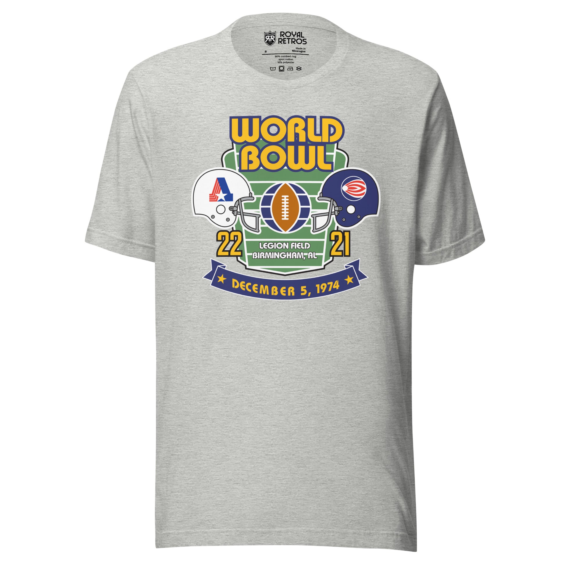 World Football League World Bowl T-shirt. Gray. World in Gold above Bowl in Gold over top of vertical football field. White helmet to left with A formed by red stripes on left, blue bar on right, star at bottom. On the right, blue helmet with white dot with white and red stripes leading a way. between helmets is a football vertical with partial globe quarters on blue on wither side. 22 in gold below white helmet. 21 in gold below blue helmet. Between numbers on bottom of football field Legion Field.