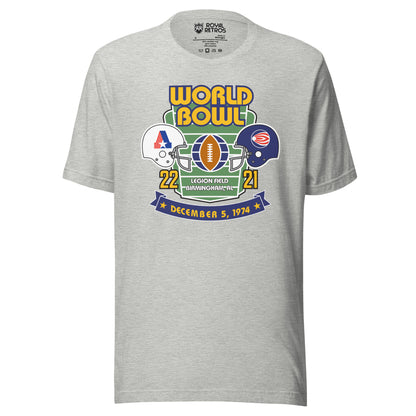 World Football League World Bowl T-shirt. Gray. World in Gold above Bowl in Gold over top of vertical football field. White helmet to left with A formed by red stripes on left, blue bar on right, star at bottom. On the right, blue helmet with white dot with white and red stripes leading a way. between helmets is a football vertical with partial globe quarters on blue on wither side. 22 in gold below white helmet. 21 in gold below blue helmet. Between numbers on bottom of football field Legion Field.