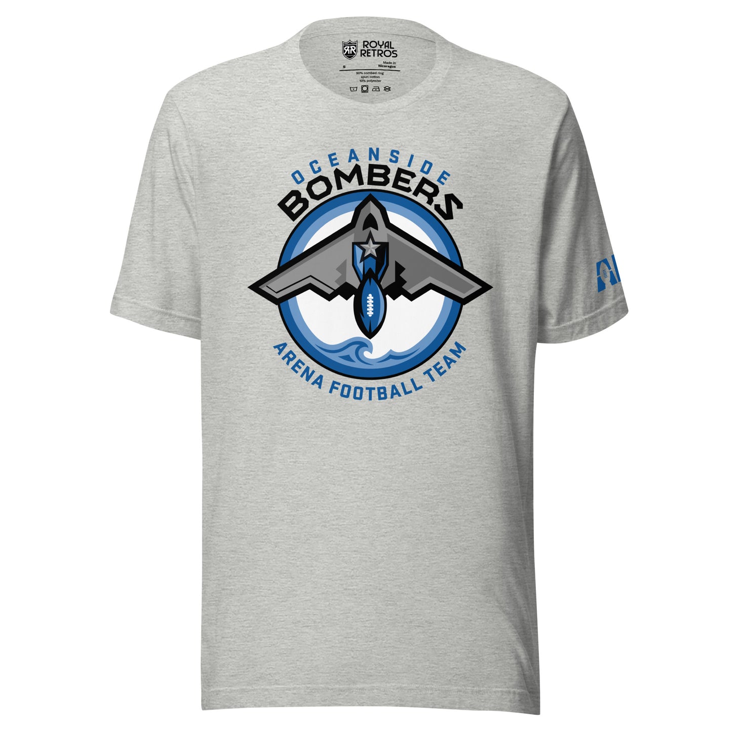 Oceanside Bombers football T-shirt. Gray. Oceanside in blue arched above Bombers slightly larger in black over a circle outlined in white and two slightly larger rings, blue and light blue inside. White background. B-2 bomber from the top over the circle with wings slightly protruding. A football coming off the tail. An ocean wave appears in the bottom of the circle. Outside the circle arched below is Arena Football team arched up in blue. Royal Retros
