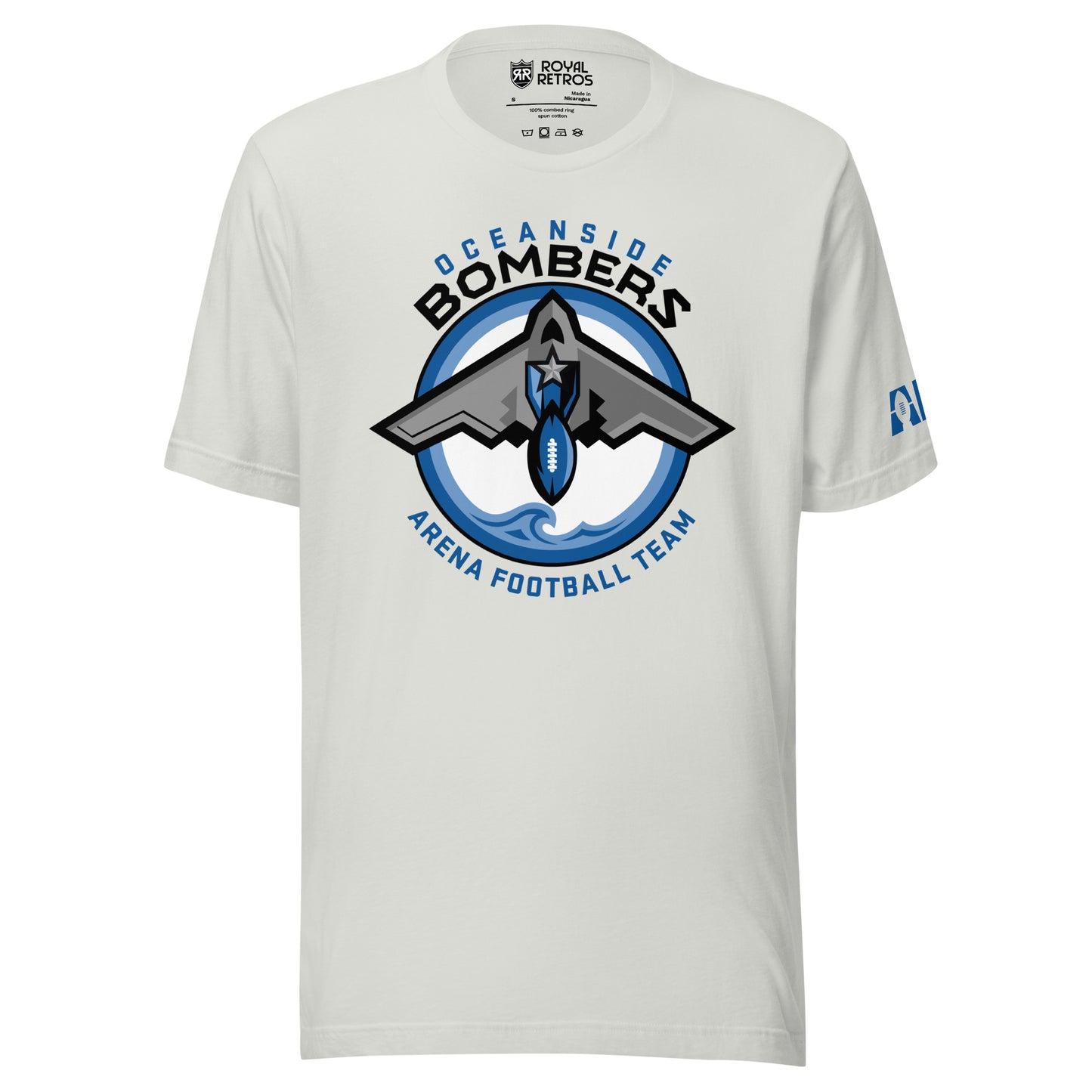 Oceanside Bombers football T-shirt. Grey. Oceanside in blue arched above Bombers slightly larger in black over a circle outlined in white and two slightly larger rings, blue and light blue inside. White background. B-2 bomber from the top over the circle with wings slightly protruding. A football coming off the tail. An ocean wave appears in the bottom of the circle. Outside the circle arched below is Arena Football team arched up in blue. Royal Retros