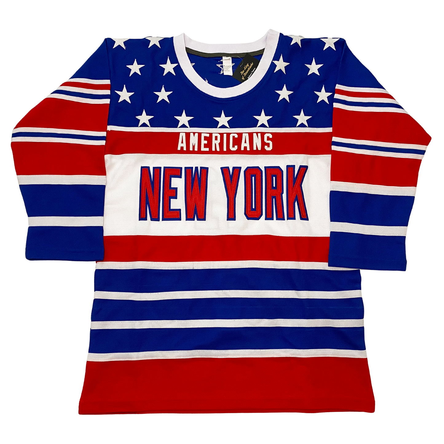 New York Americans hockey jersey. White collar. Blue shoulders with white stars, Alternating red, white, and blue bands of various sizes on sleeves and on bottom half of jersey. Americans in white on red band across chest. Large white band below with New York in red with blue trim. Royal Retros