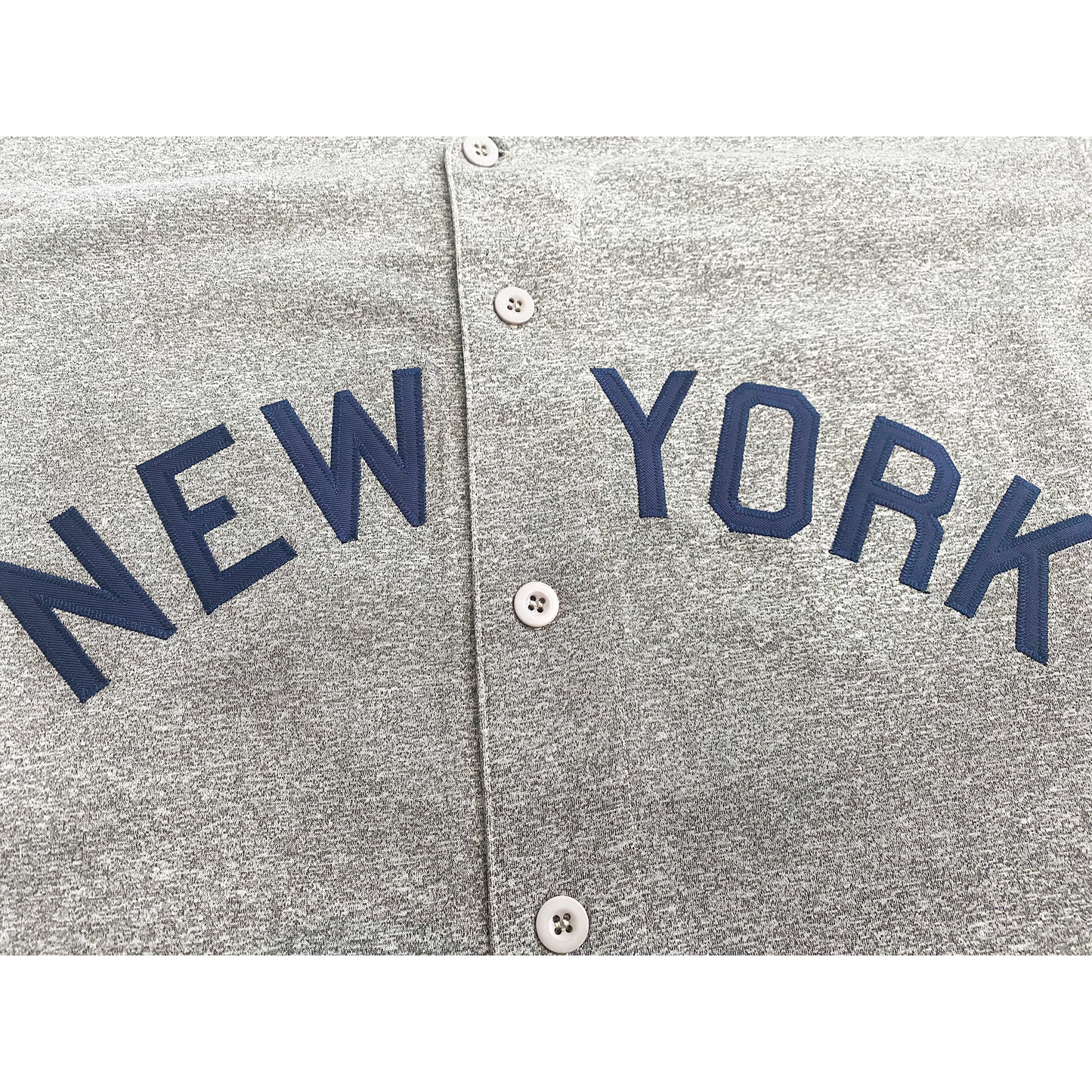 New York Yankees button-up  jersey. Road pepper gray. Close-up of New York in blue across chest.