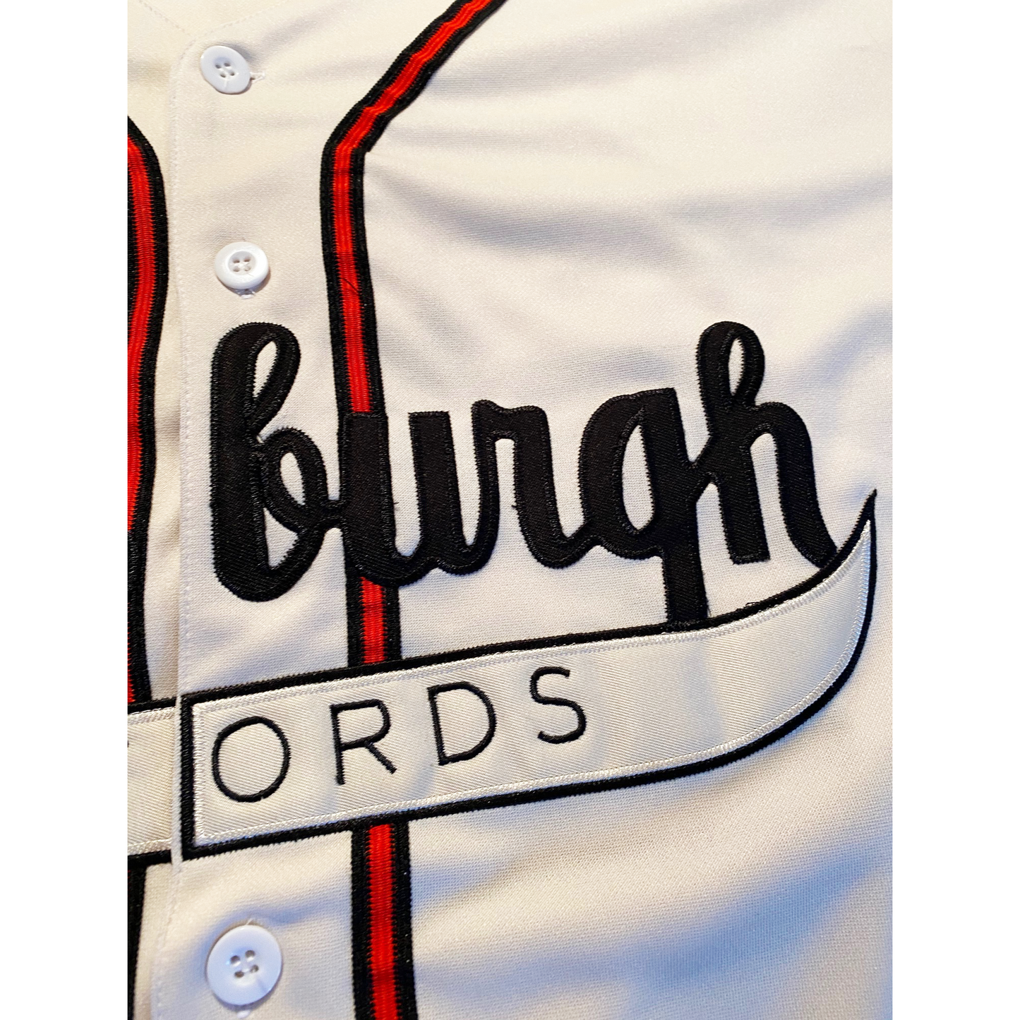 Pittsburgh Crawfords button-up baseball jersey. White close up of cursive "burgh" in black. Black, red, and black stripes on either side of buttons. Royal Retros