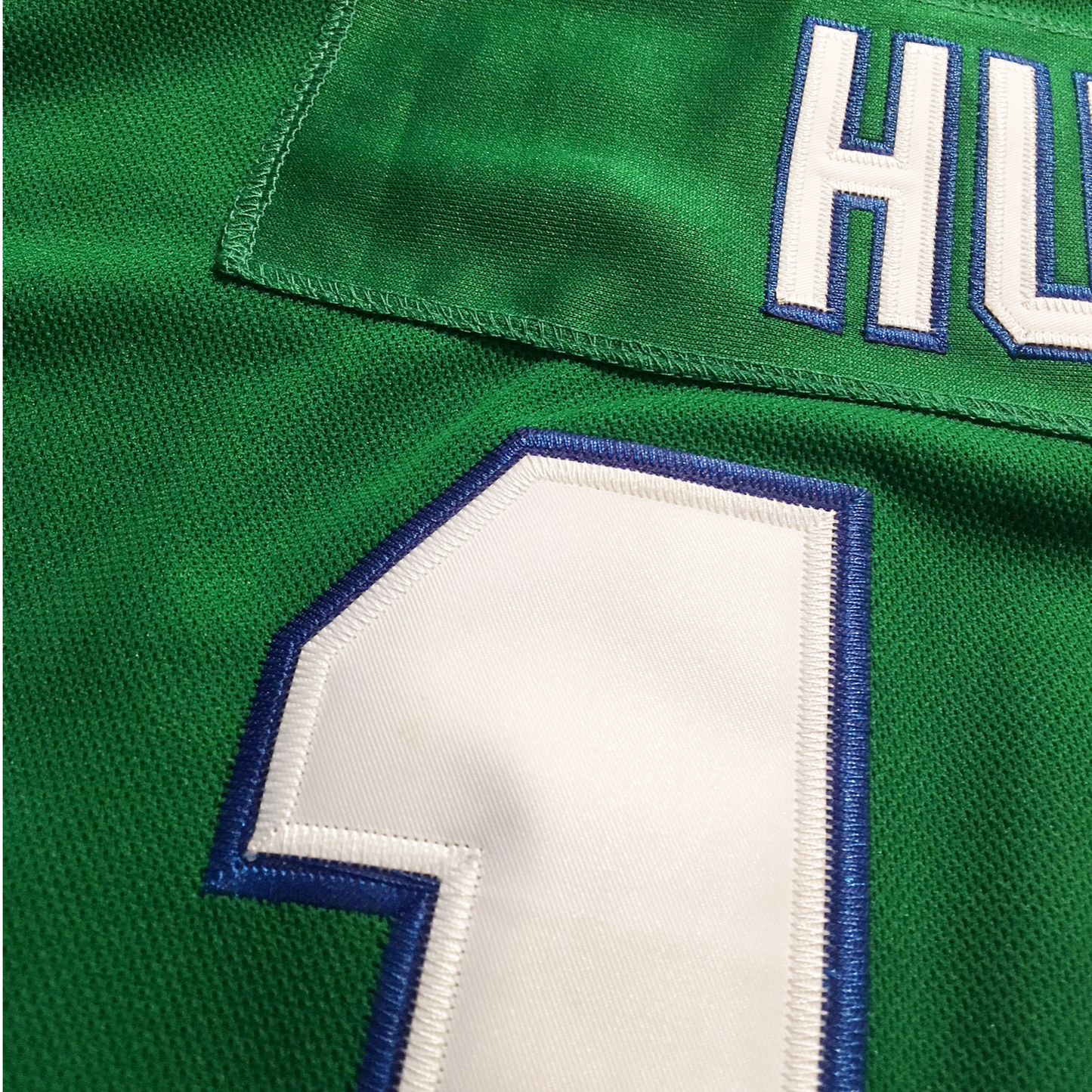 1979-91 Whalers Jersey close-up green of stitching of numbers and letters in white with blue trim on green jersey. Royal Retros